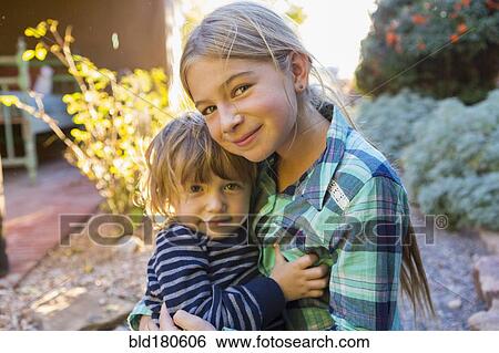 Stock Photograph - Caucasian brother and sister hugging outdoors. Fotosearch
