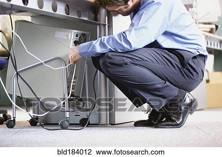 Caucasian businessman connecting cables to computer in office View Large Photo Image Stock Image - Caucasian businessman connecting cables to computer in office. Fotosearch