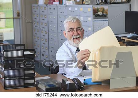 Caucasian businessman filing folders in office View Large Photo Image Picture - Caucasian businessman filing folders in office. Fotosearch