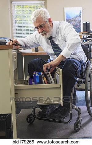 Stock Photography - Caucasian businessman filing papers at desk. Fotosearch