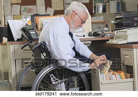 Stock Image - Caucasian businessman filing papers in office. Fotosearch