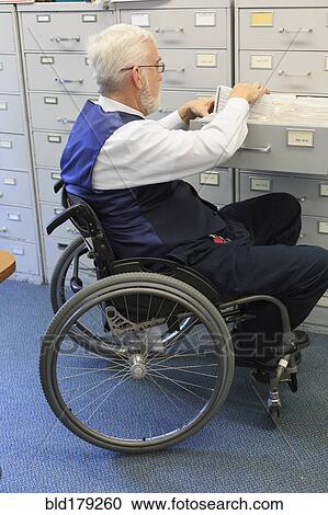 Stock Image - Caucasian businessman filing papers in office. Fotosearch