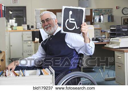 Stock Photo - Caucasian businessman holding handicapped sign in office. Fotosearch