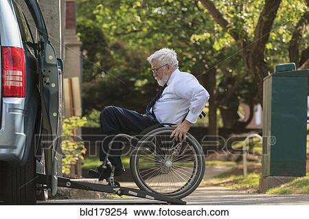 Picture - Caucasian businessman in wheelchair entering van. Fotosearch