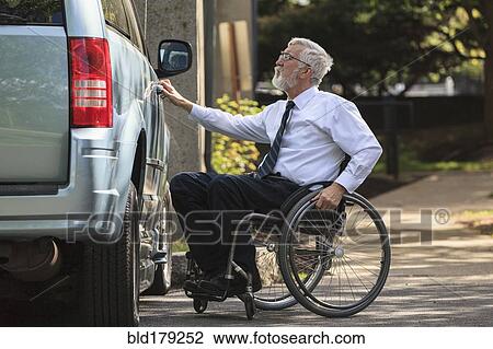 Stock Image - Caucasian businessman in wheelchair opening van door. Fotosearch