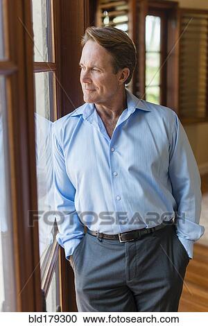 Stock Image - Caucasian businessman looking out window. Fotosearch