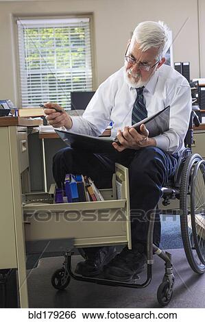 Caucasian businessman reading binder at desk View Large Photo Image Stock Photograph - Caucasian businessman reading binder at desk. Fotosearch