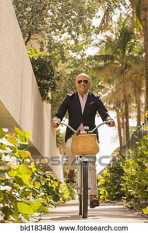 Stock Image - Caucasian businessman riding bicycle. Fotosearch