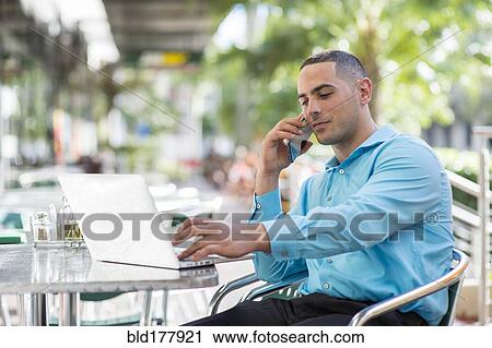 Stock Image - Caucasian businessman talking on cell phone in cafe. Fotosearch