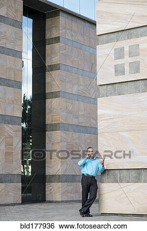 Stock Photograph - Caucasian businessman talking on cell phone outdoors. Fotosearch