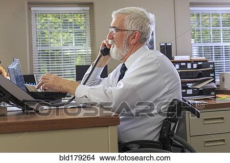 Picture - Caucasian businessman talking on phone at desk. Fotosearch