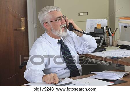 Stock Image - Caucasian businessman talking on phone in office. Fotosearch