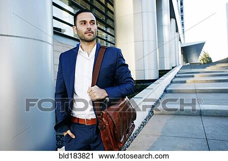 Stock Image - Caucasian businessman walking outside office building. Fotosearch