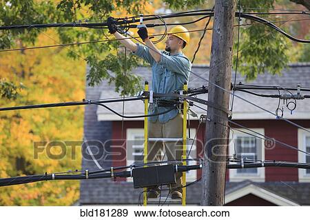 Stock Photo - Caucasian cable installer working on ladder. Fotosearch