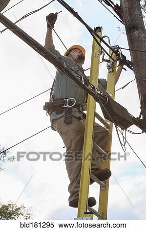 Stock Photography - Caucasian cable installer working on ladder. Fotosearch