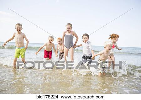 Caucasian children playing in waves on beach View Large Photo Image Picture - Caucasian children playing in waves on beach. Fotosearch