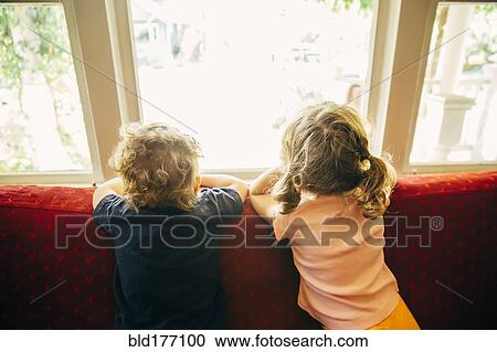 Stock Image - Caucasian children standing on sofa. Fotosearch