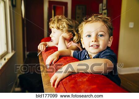 Stock Photo - Caucasian children standing on sofa. Fotosearch