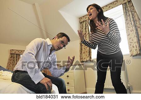 Stock Image - Caucasian couple arguing in bedroom. Fotosearch