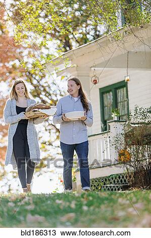 Stock Image - Caucasian couple carrying food in backyard. Fotosearch