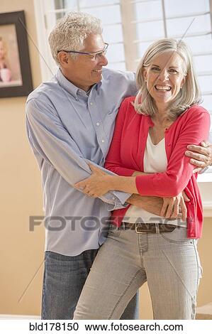 Stock Image - Caucasian couple dancing in living room. Fotosearch