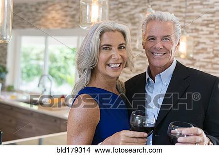 Picture - Caucasian couple drinking wine in kitchen. Fotosearch