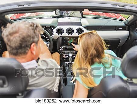 Stock Image - Caucasian couple driving convertible. Fotosearch