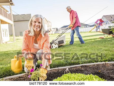 Stock Image - Caucasian couple gardening in backyard. Fotosearch