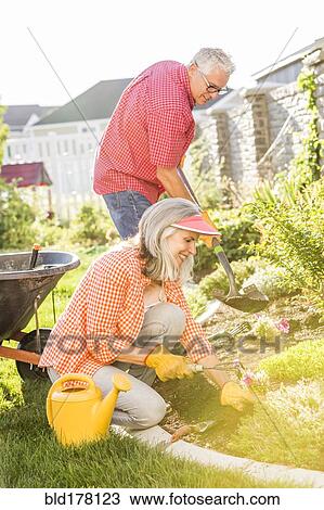 Stock Image - Caucasian couple gardening in backyard. Fotosearch