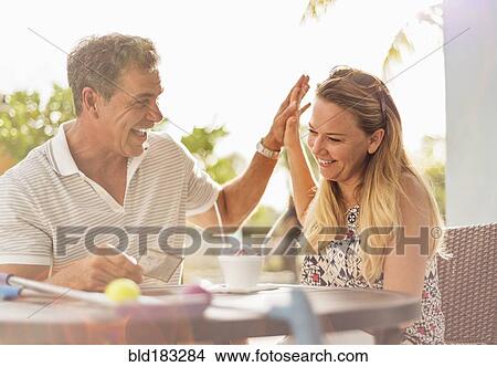 Picture - Caucasian couple high-fiving at outdoor table. Fotosearch