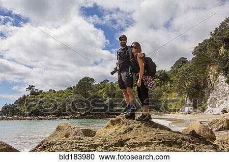 Stock Image - Caucasian couple hiking on remote beach. Fotosearch