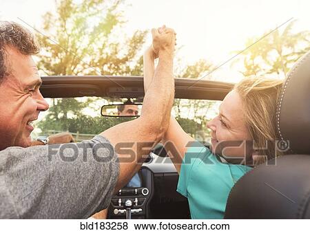 Stock Photo - Caucasian couple holding hands in convertible. Fotosearch