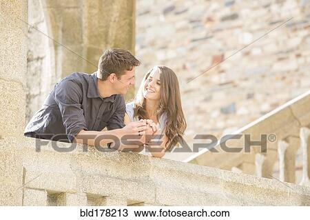 Stock Image - Caucasian couple leaning on balcony. Fotosearch