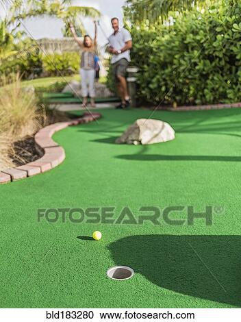 Stock Image - Caucasian couple playing miniature golf. Fotosearch
