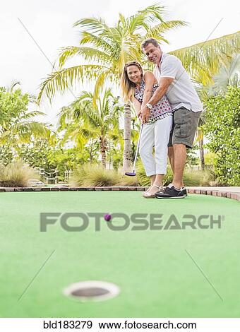 Stock Photo - Caucasian couple playing miniature golf. Fotosearch