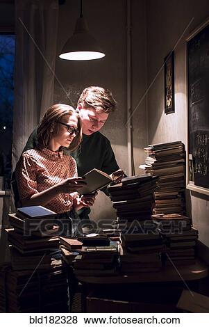 Stock Photo - Caucasian couple reading stack of books. Fotosearch