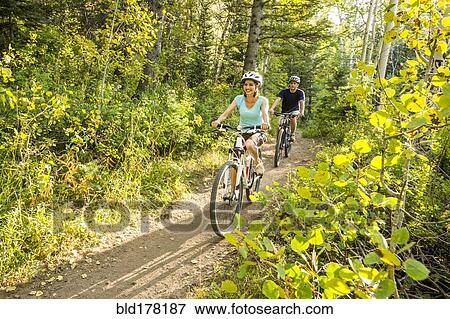 Stock Photo - Caucasian couple riding mountain bikes. Fotosearch