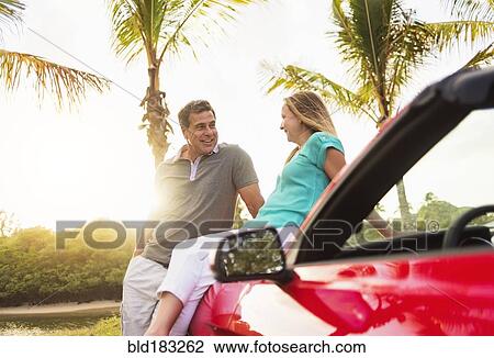 Stock Image - Caucasian couple sitting on convertible. Fotosearch