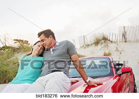 Stock Photograph - Caucasian couple sitting on convertible. Fotosearch