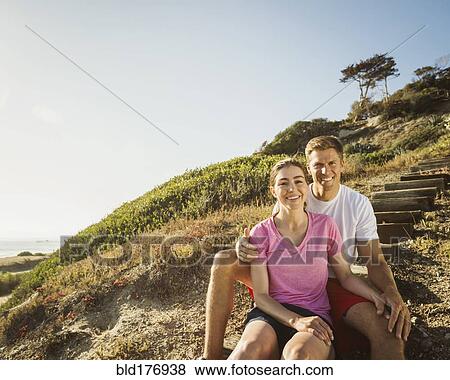 Stock Photo - Caucasian couple sitting on hillside. Fotosearch