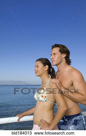 Stock Image - Caucasian couple standing on boat deck. Fotosearch