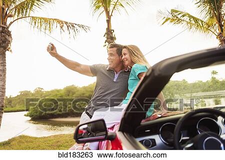 Caucasian couple taking selfie on convertible View Large Photo Image Stock Image - Caucasian couple taking selfie on convertible. Fotosearch