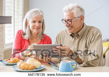 Stock Photography - Caucasian couple using digital tablet at table. Fotosearch