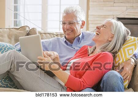 Stock Image - Caucasian couple using laptop on sofa. Fotosearch