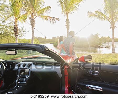 Stock Photo - Caucasian couple walking near convertible. Fotosearch