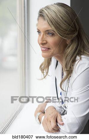 Caucasian doctor looking out window View Large Photo Image Stock Photo - Caucasian doctor looking out window. Fotosearch