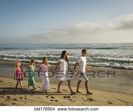 Picture - Caucasian family holding hands on beach. Fotosearch