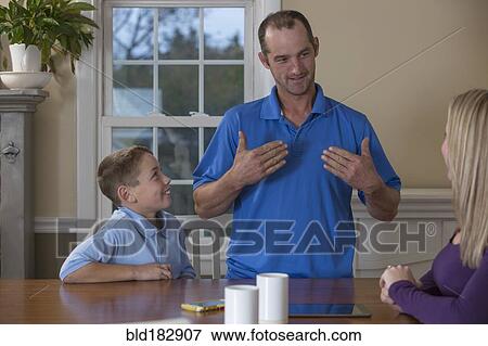 Caucasian family signing at dinner table View Large Photo Image Stock Photo - Caucasian family signing at dinner table. Fotosearch