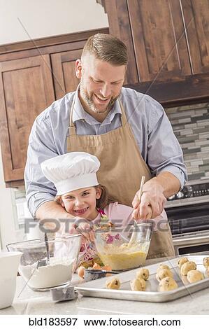 Stock Photo - Caucasian father and daughter baking in kitchen. Fotosearch