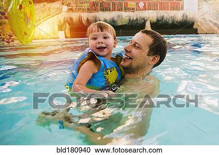 Stock Image - Caucasian father and daughter swimming in pool. Fotosearch